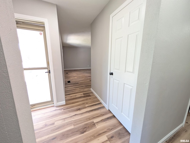 hall featuring light wood-type flooring and baseboards
