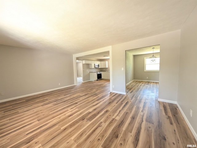unfurnished living room featuring wood finished floors and baseboards