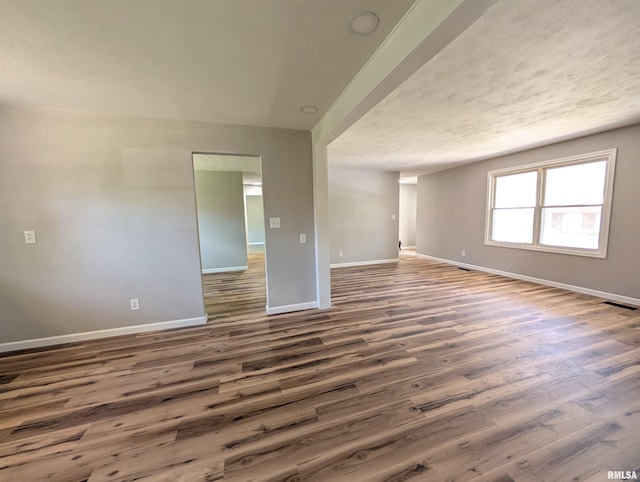 empty room featuring baseboards, wood finished floors, and a textured ceiling