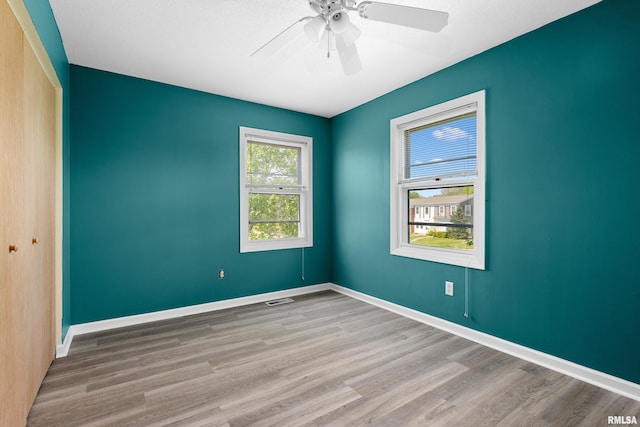spare room featuring wood finished floors, ceiling fan, and baseboards