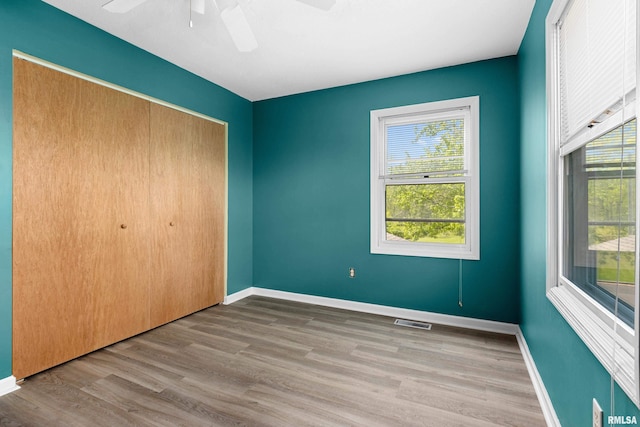 unfurnished bedroom with baseboards, wood finished floors, a closet, and ceiling fan