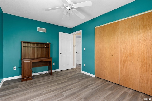 unfurnished bedroom featuring wood finished floors, baseboards, a closet, and ceiling fan