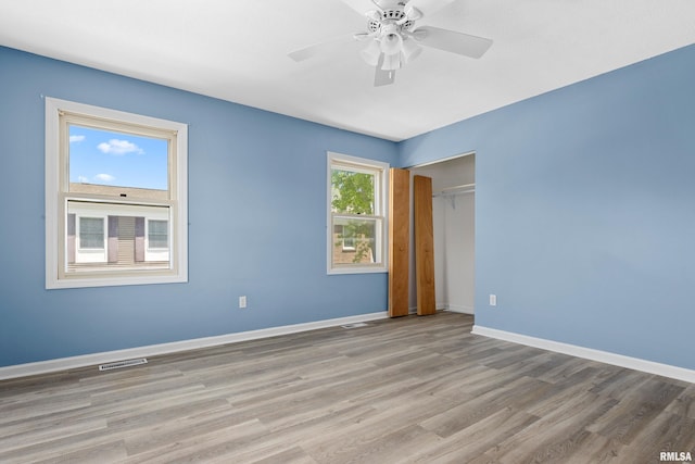 unfurnished bedroom featuring wood finished floors, baseboards, a closet, and ceiling fan