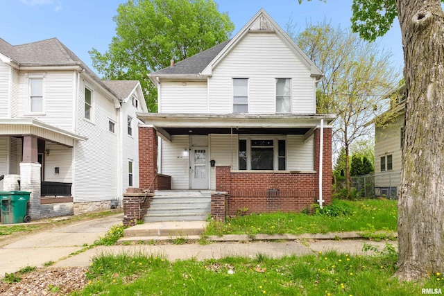 american foursquare style home featuring a porch and brick siding