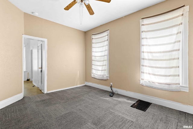 carpeted spare room featuring a ceiling fan and baseboards
