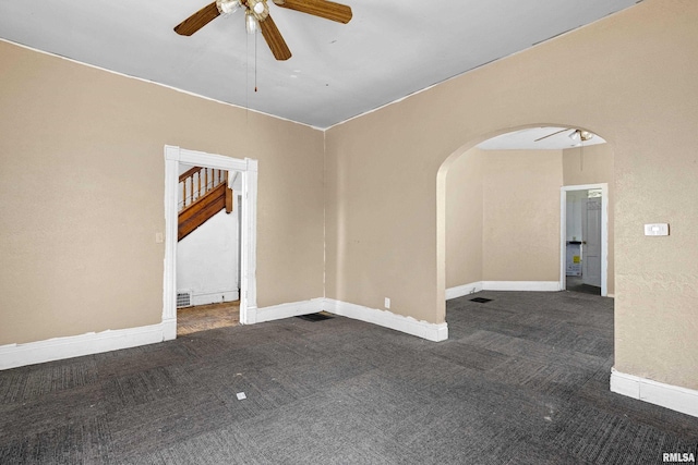 carpeted spare room with ceiling fan, arched walkways, and baseboards