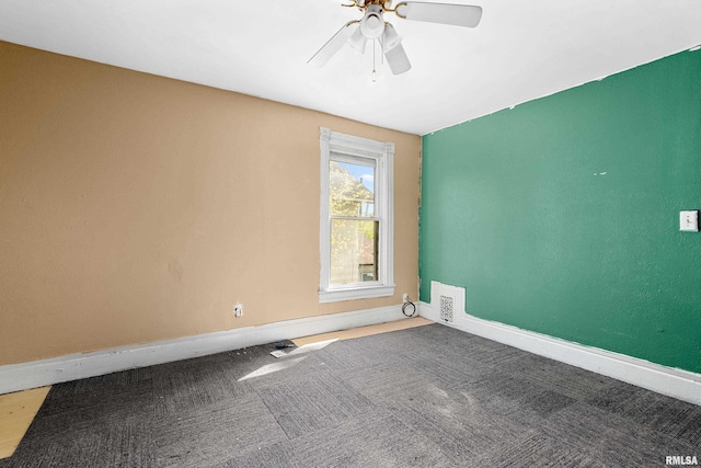 carpeted spare room featuring ceiling fan and baseboards