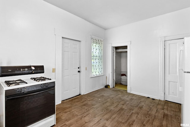 kitchen featuring gas range, wood finished floors, and baseboards