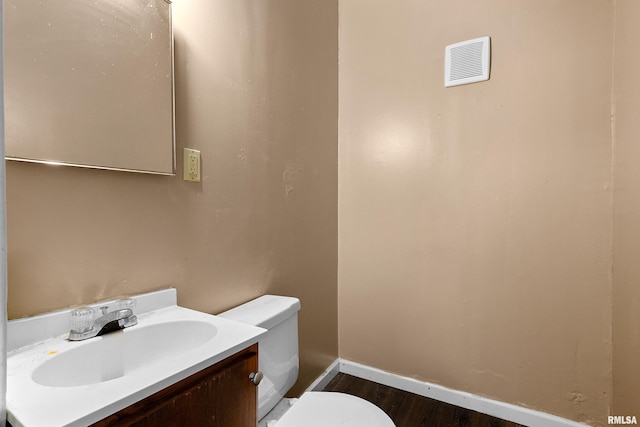 bathroom featuring toilet, wood finished floors, vanity, and baseboards