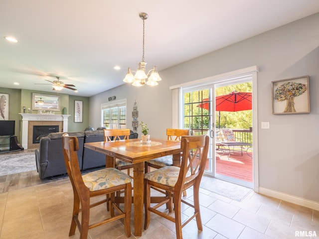 dining room featuring recessed lighting, a tiled fireplace, baseboards, a ceiling fan, and a chandelier