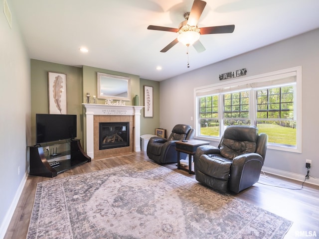 living area featuring baseboards, a tiled fireplace, ceiling fan, wood finished floors, and recessed lighting