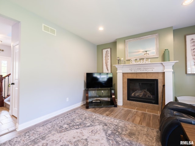 living area featuring wood finished floors, a tiled fireplace, recessed lighting, and baseboards