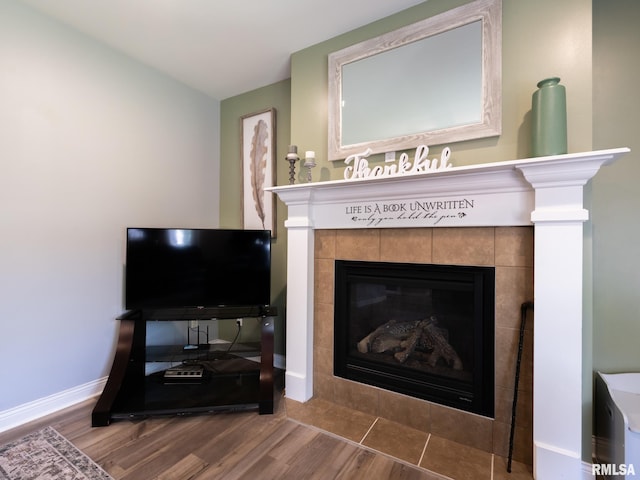 detailed view of a tile fireplace, wood finished floors, and baseboards