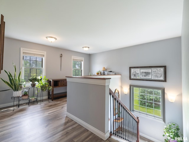 corridor with wood finished floors, baseboards, and an upstairs landing