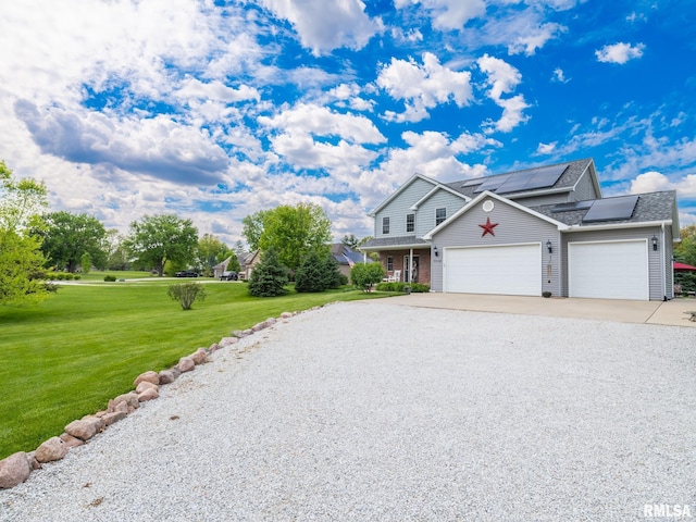traditional home with a front lawn, concrete driveway, an attached garage, roof mounted solar panels, and roof with shingles