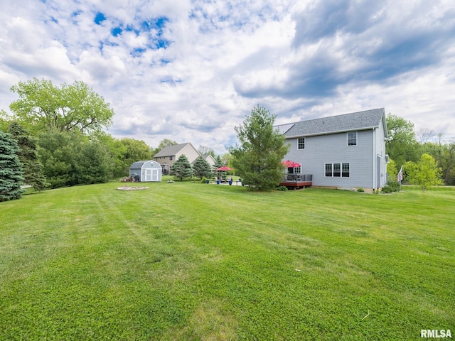 view of green lawn with an outbuilding, a storage shed, and a wooden deck