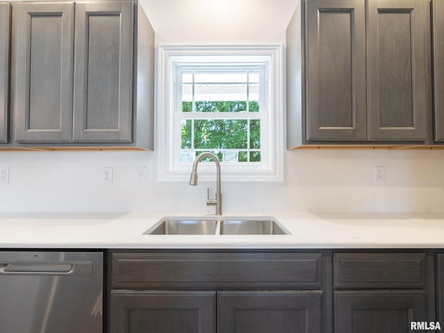 kitchen with stainless steel dishwasher, a sink, and light countertops