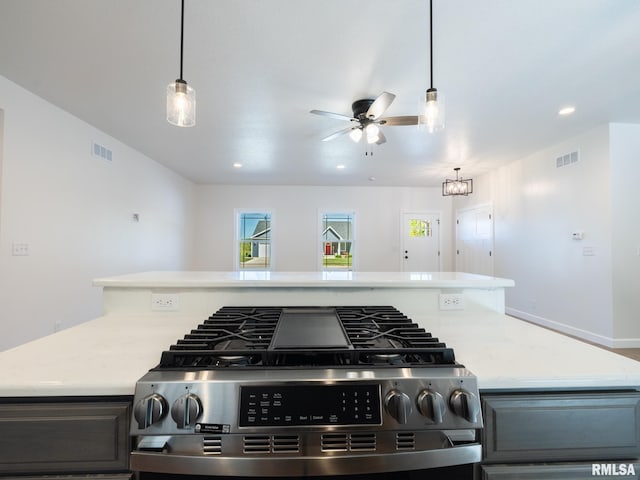 kitchen featuring recessed lighting, a ceiling fan, stainless steel gas range, light stone counters, and hanging light fixtures