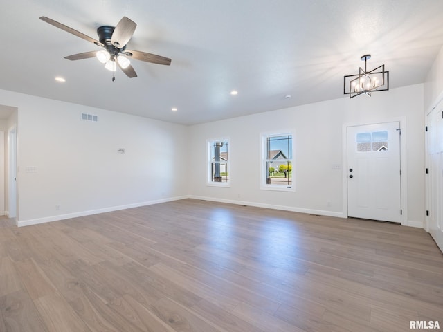 unfurnished living room with light wood-type flooring, a chandelier, baseboards, a ceiling fan, and recessed lighting