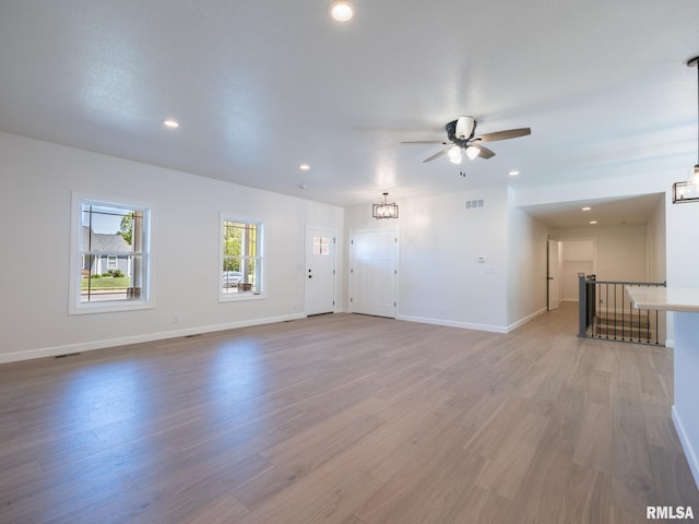 unfurnished living room featuring ceiling fan, recessed lighting, light wood-style flooring, baseboards, and a chandelier