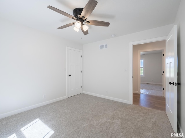 carpeted spare room featuring a ceiling fan and baseboards