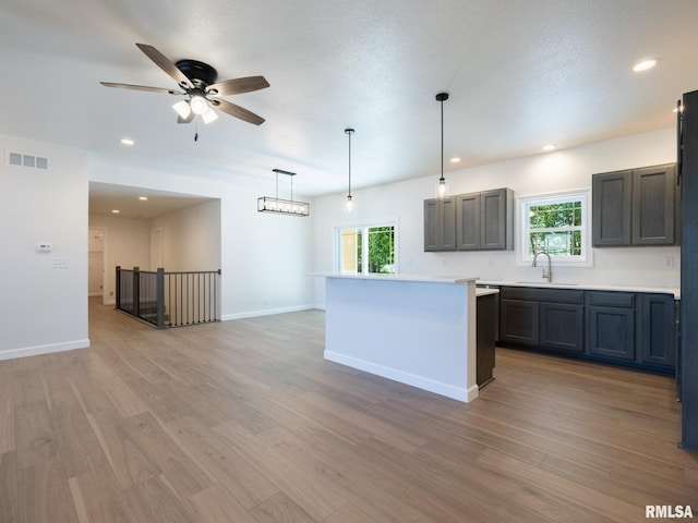 kitchen featuring a sink, light wood finished floors, healthy amount of natural light, light countertops, and recessed lighting