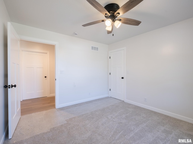 unfurnished room with light colored carpet, a ceiling fan, and baseboards