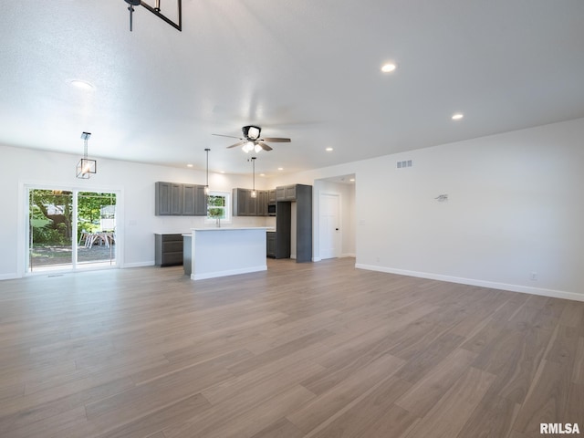 unfurnished living room with a ceiling fan, recessed lighting, baseboards, and light wood-style flooring