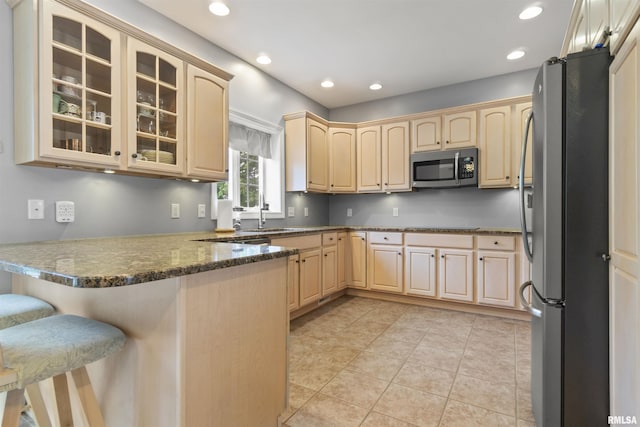 11506 N Bristol Dr, Dunlap, IL 61525 - kitchen featuring stainless steel appliances, light brown cabinets, a peninsula, glass insert cabinets, and a breakfast bar
