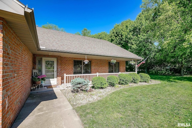 15207 N 7th St, Chillicothe, IL 61523 - property entrance with a porch, brick siding, a shingled roof, and a yard
