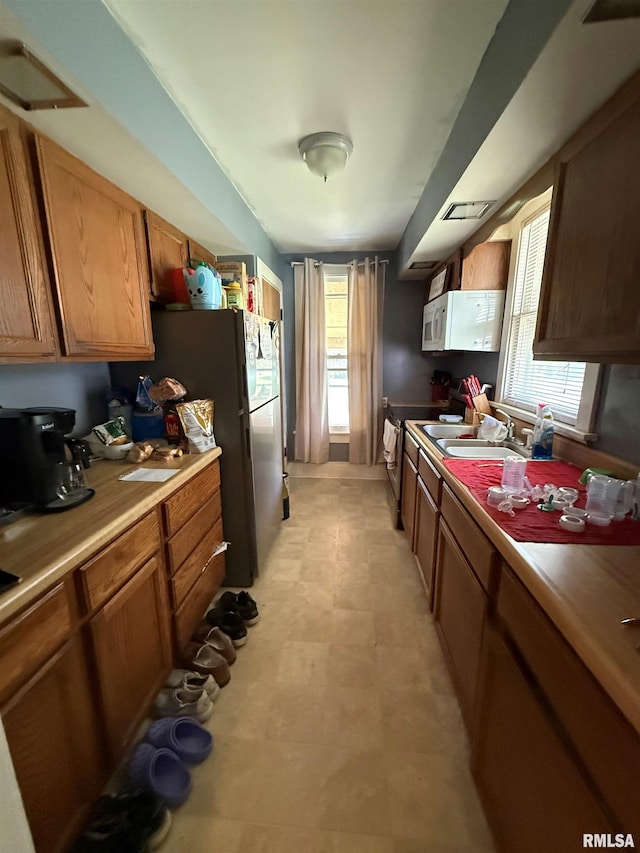 411 W Jefferson St, Macomb, IL 61455 - kitchen with a sink, white microwave, electric stove, brown cabinetry, and light countertops