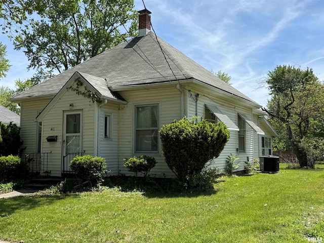 411 W Jefferson St, Macomb, IL 61455 - view of front of house with central AC, a front yard, and a chimney