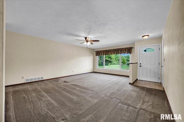 unfurnished living room with carpet, a ceiling fan, a textured ceiling, and baseboards