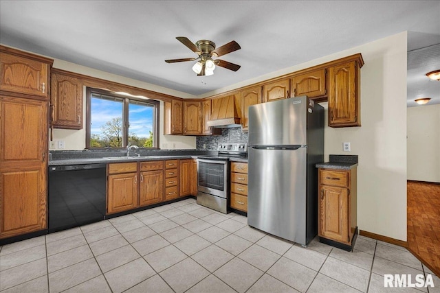 kitchen featuring stainless steel appliances, dark countertops, a sink, and brown cabinetry