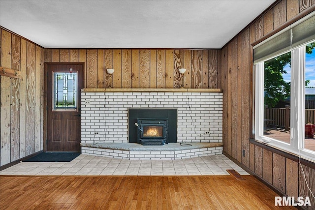 unfurnished living room with wood finished floors, plenty of natural light, baseboards, and wood walls