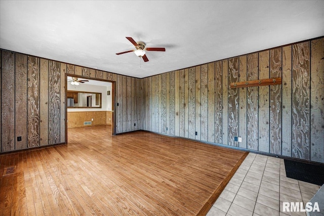 empty room featuring a ceiling fan and wood walls