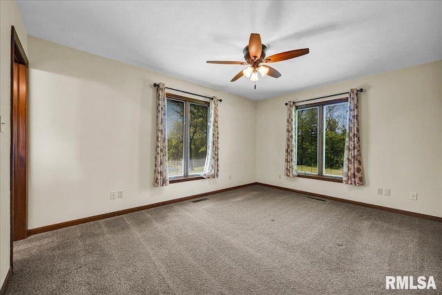carpeted spare room featuring plenty of natural light, baseboards, and a ceiling fan