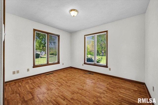 unfurnished room with plenty of natural light, wood finished floors, and baseboards