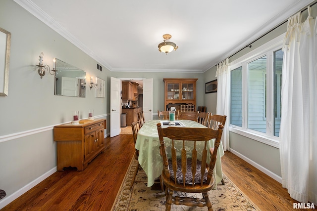 dining area featuring dark wood finished floors, baseboards, and crown molding