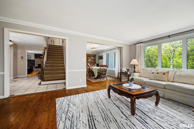 living area with stairs, crown molding, wood finished floors, and baseboards