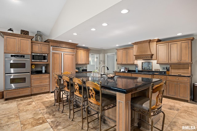 kitchen with built in appliances, custom range hood, recessed lighting, a sink, and a breakfast bar
