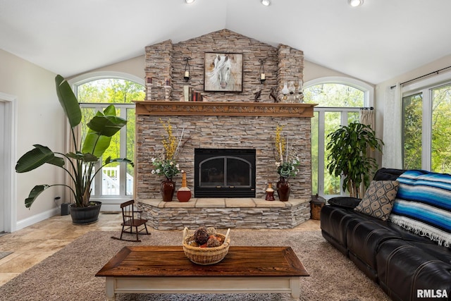 living room featuring lofted ceiling, a stone fireplace, and baseboards