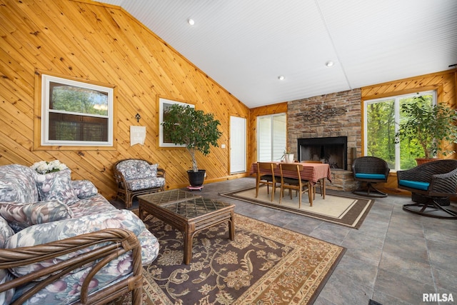living room featuring wooden walls, stone finish floors, high vaulted ceiling, a fireplace, and recessed lighting