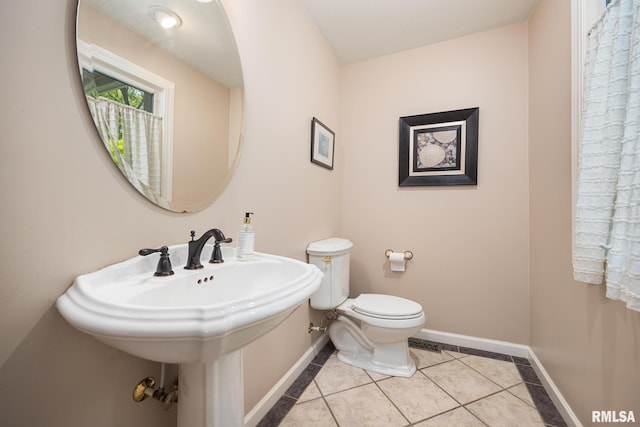 bathroom featuring toilet, baseboards, tile patterned flooring, and a sink