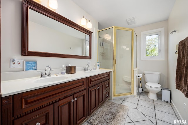 bathroom featuring tile patterned floors, a stall shower, double vanity, and toilet