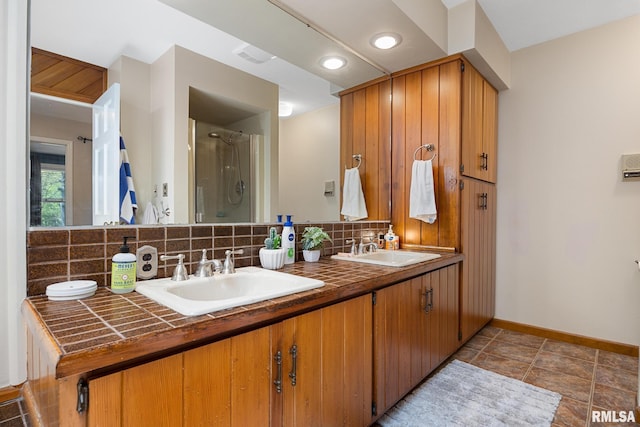 full bath with a stall shower, decorative backsplash, baseboards, and double vanity
