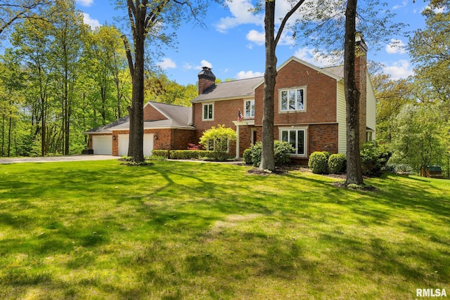 view of front of home featuring a chimney, an attached garage, driveway, and a front lawn