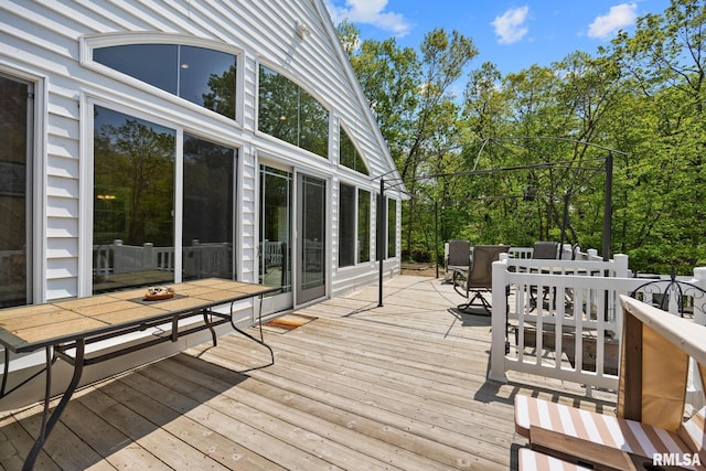 wooden terrace with outdoor dining area and view of scattered trees