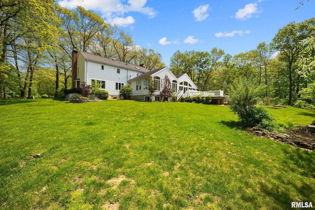 view of green lawn with a wooden deck