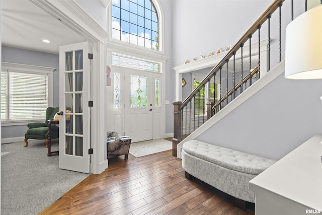 foyer entrance with stairs, baseboards, hardwood / wood-style floors, a high ceiling, and recessed lighting